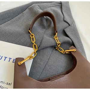 Détail d'un sac cabas en cuir marron avec texture litchi et bandoulière dorée