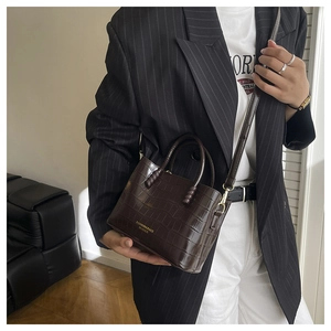 Détail d'un cabas en cuir à motif crocodile marron foncé avec lettrage doré sur le modèle