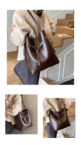 Detail view of large dark brown leather bucket bag with gold hardware and strap buckles