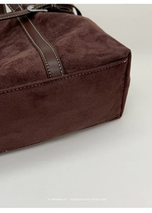 Detail of dark brown suede tote bag featuring contrast stitching and leather trim accents
