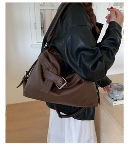 Detail of dark brown leather tote featuring buckle strap and vintage motorcycle style