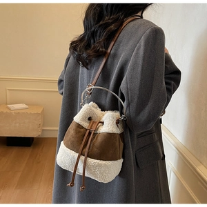 Detailed texture of white plush faux fur and brown suede on a bucket bag with metal ring