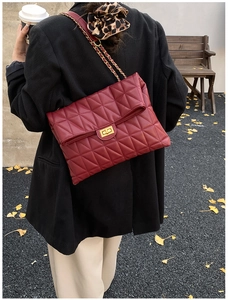 Detail of burgundy quilted chain bag with gold twist lock worn with a black blazer