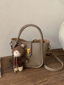 Taupe pebbled leather bucket bag with gold hardware and a cute bear charm accessory