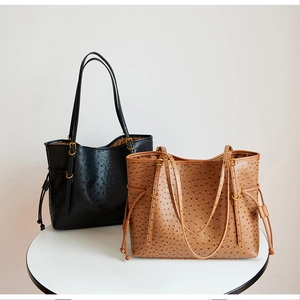 Close-up of ostrich-textured tote bags in black and brown with sleek long straps