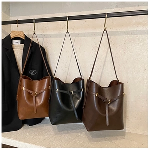 Detailed display of bucket bags in brown, black, and chocolate brown with belt buckles