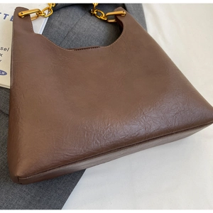 Détail du sac cabas marron foncé avec texture en cuir plissé et bandoulière chaîne dorée