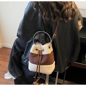 Detail of faux shearling and brown suede bucket bag with metal handle and drawstring