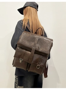 Rear view of model wearing a vintage dark brown wax leather backpack with magnetic buckles