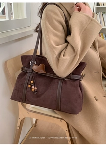 Detail of retro suede tote bag with leather buckle and heart fringe charm decoration