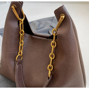 Détail du sac cabas marron foncé avec texture mate et chaîne à maillons dorés