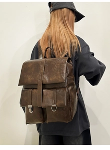 Detail view of large vintage brown leather backpack with front pockets on female model