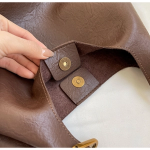 Détail montrant le fermoir magnétique double et la doublure du cabas en cuir marron foncé