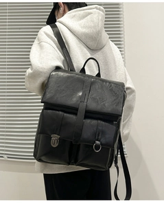 Detail view of stylish black faux leather backpack featuring front pockets and buckle straps