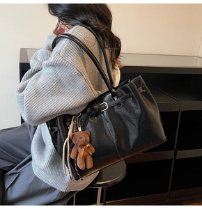Detail of vintage pleated leather tote bag with a cute plush bear charm on shoulder