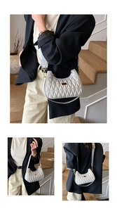 Detail of white quilted half-moon bag with gold metal plaque and wide woven strap