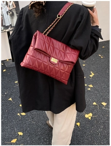 Macro view of burgundy quilted shoulder bag featuring gold chain and turn-lock closure