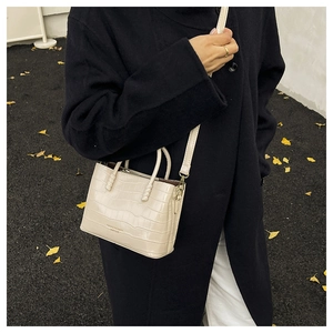 Détail d'un sac cabas en cuir gaufré crocodile blanc crème avec décoration de texte