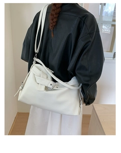 Close-up of white pebble leather hobo bag with metal buckle detail and knotted strap