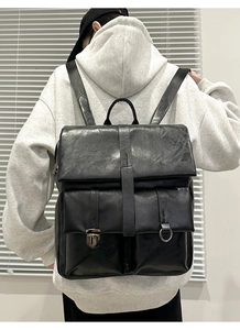 Detail view of a black vintage PU leather backpack with double metal buckle front pockets