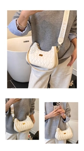 Close-up of quilted cream half-moon bag with wide letter strap and gold hardware accents