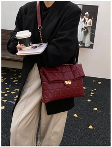 Close-up of wine red quilted shoulder bag with gold twist lock and chain strap