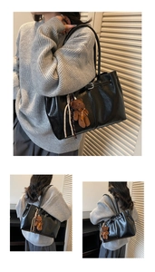 Detail of black faux leather tote bag with metallic buckle and plush bear pendant