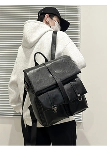 Detail of black matte leather backpack featuring hardware buckles and straps on a model