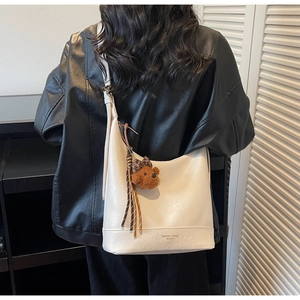 Detail of cream hobo bag with plush bear charm and Fashion Trend lettering