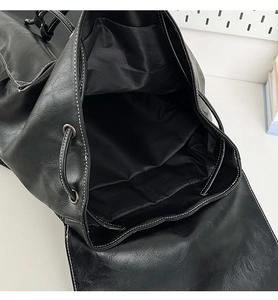 Close-up of black leather backpack with drawstring closure and white contrast stitching
