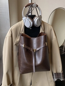 Large brown vintage leather tote bag shown with trench coat and headphones