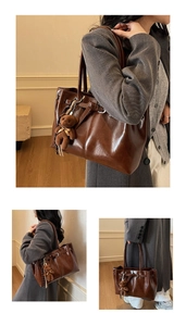 Detail of dark brown glossy leather tote with adjustable buckle and bear charm
