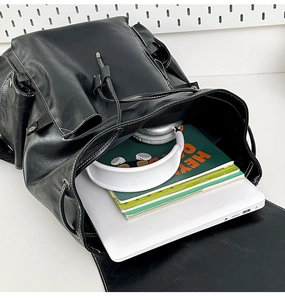 Large capacity black PU leather backpack showing a 14-inch laptop and magazines inside