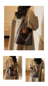 Detail of vintage brown tote bag featuring soft faux leather and plush bear charm