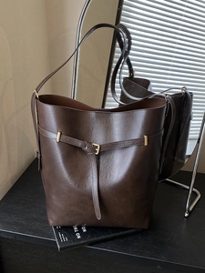 Minimalist deep brown leather bucket bag with gold buckle and adjustable strap