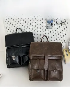 Detail view of large front pockets and metal buckle on vintage PU leather backpack