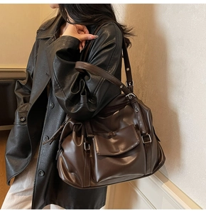 Detail of dark brown leather tote bag showing large capacity and side metal rings