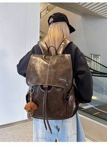Detailed view of vintage dark brown backpack with teddy bear charm and side pockets