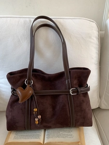 Deep brown matte suede tote bag with heart charm and wood beads on a vintage book