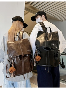 Detail of vintage high-capacity backpacks in brown and black PU leather with plush charm