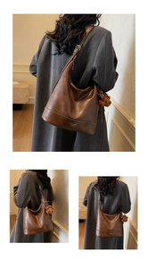 Detail of a brown hobo bag featuring a plush bear charm and Fashion Trend embossed text