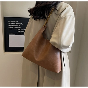 Détail d'un sac Hobo marron avec texture cuir vintage et une épaisse chaîne en métal doré