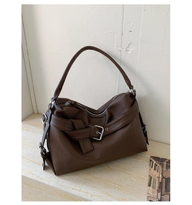 Detail of dark brown lychee leather tote with vintage metal buckle and silver hardware