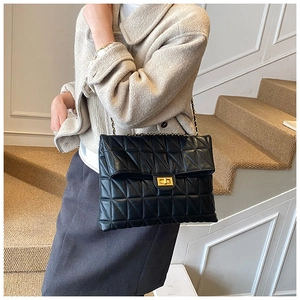 Quilted black chain bag with golden square lock worn by a model in a stylish indoor setting
