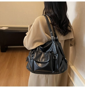 Detailed side view of black soft leather tote bag worn with a stylish khaki trench coat