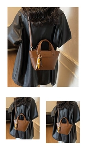 Detail view of brown bucket bag with lychee texture, wooden bead charm and crossbody strap