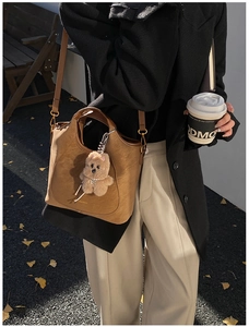 Brown vintage bucket bag detail with a plush bear charm and detachable shoulder strap