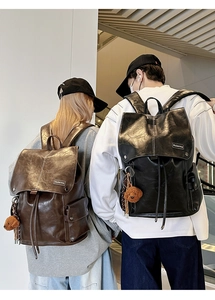 Close-up of vintage faux leather backpacks with buckle pockets and cute bear charms