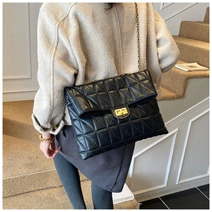 Close-up of black quilted shoulder bag with gold twist lock and elegant chain strap