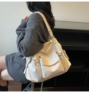 Detail of off-white leather tote bag with silver hardware and tassel charm on shoulder